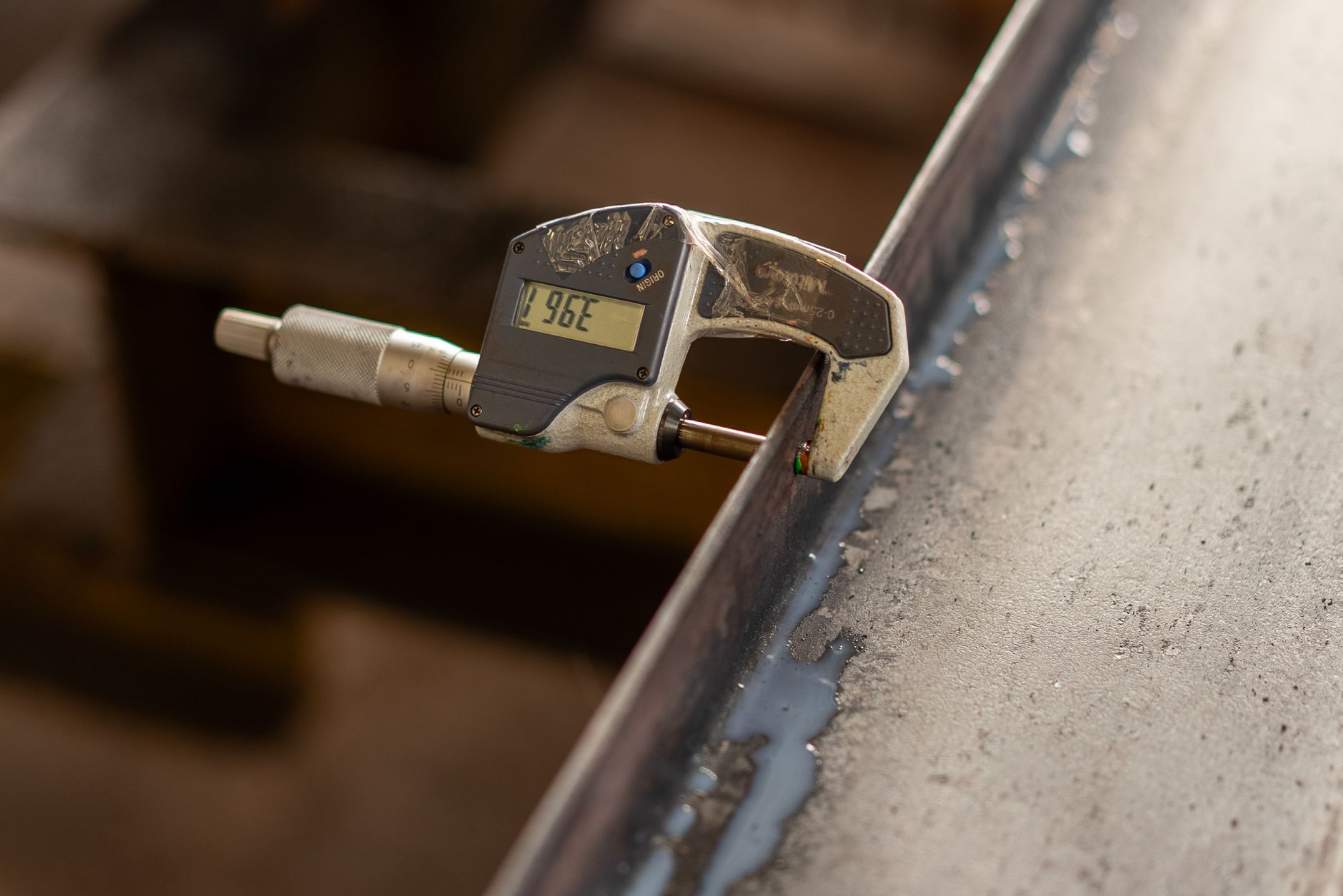 a four-foot aluminum straightedge laid across a mattress surface with a feeler gauge beside it on a bedside table