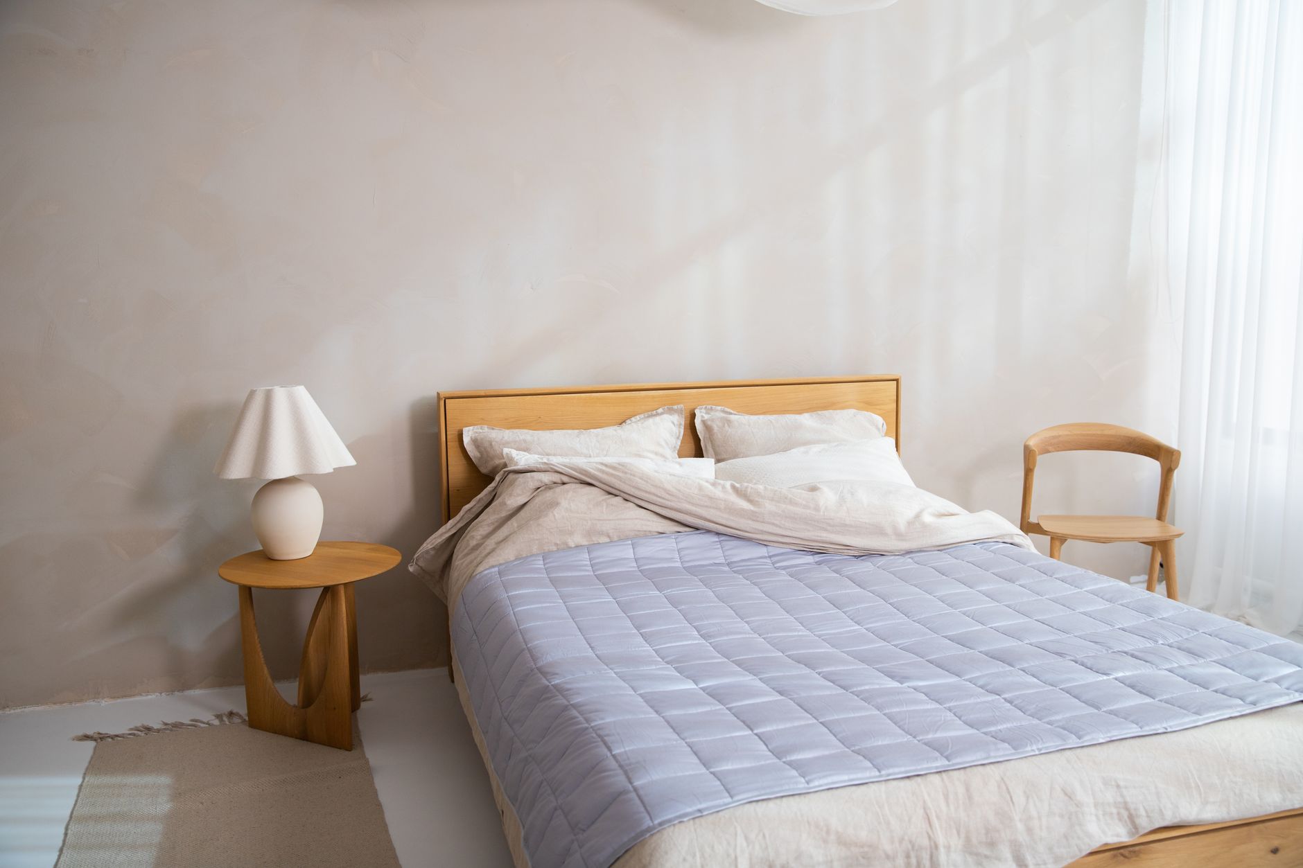 A Brooklyn Bedding Signature Hybrid mattress on a simple bed frame in a sunlit room, with a straightedge and feeler gauge resting on the corner.