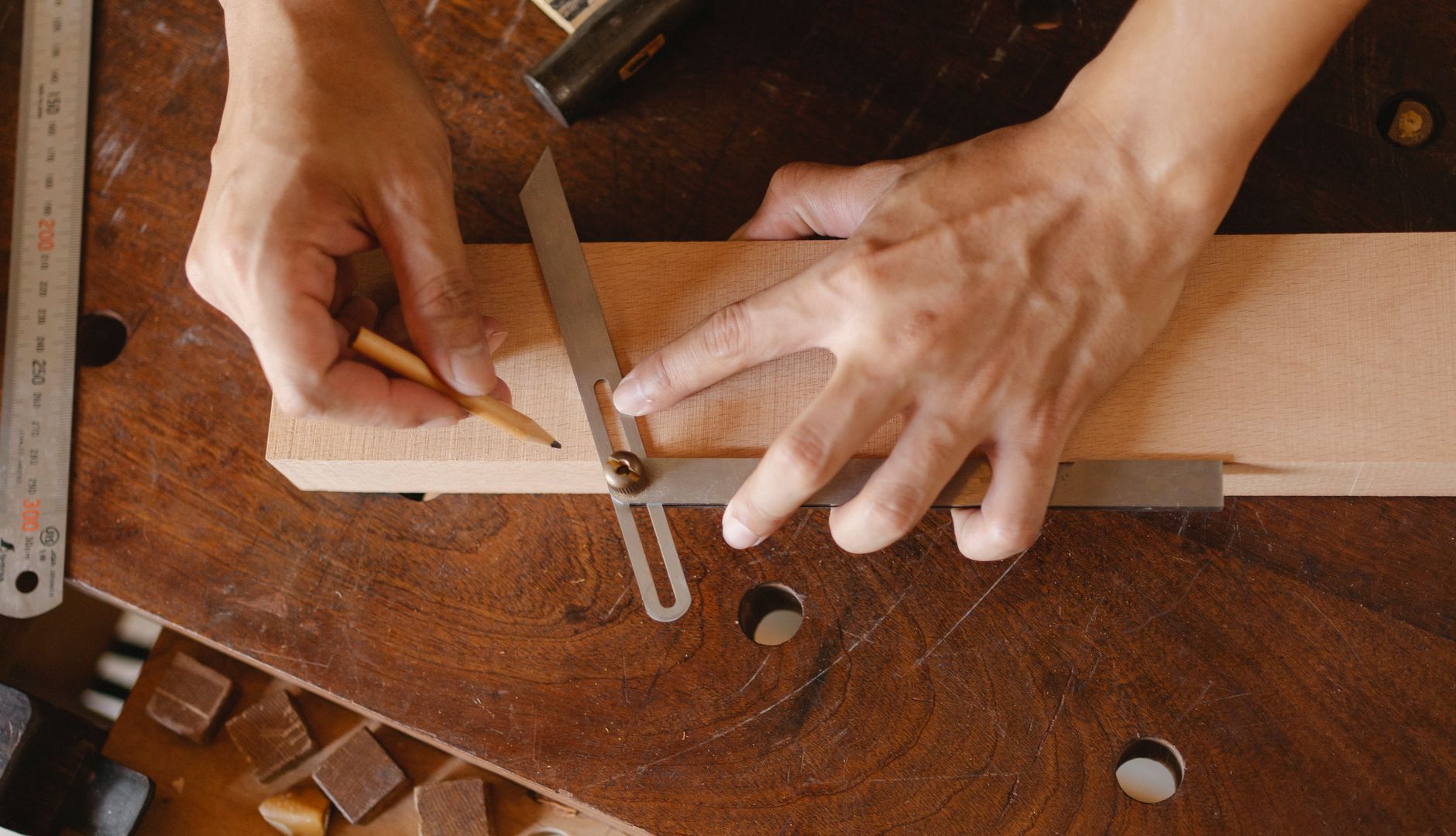 A four-foot aluminum straightedge laid across a mattress surface with a feeler gauge inserted underneath, measuring sag depth